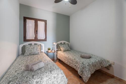 a bedroom with two beds and a window at Sunhouse El Chocito in Candelaria