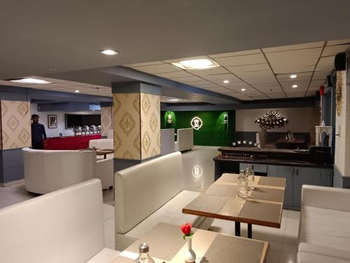 a restaurant with white chairs and tables and green walls at Hotel Amba International in Jodhpur