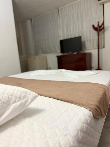 a bedroom with two white beds and a television at Hotel Xilon Resort Melgar in Melgar