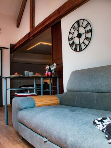 a living room with a couch and a clock on the wall at suite Alphonsine in Incourt