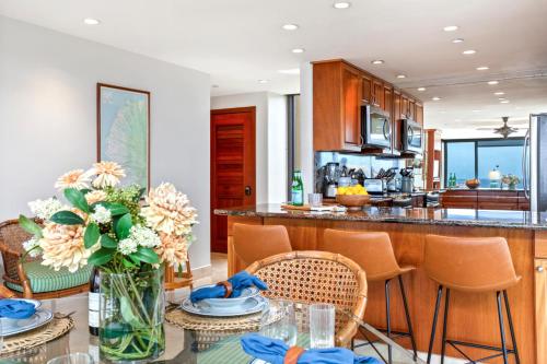 a kitchen with a table with a vase of flowers at Mahana by KBM Resorts in Kaanapali