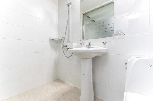 Un baño blanco con lavabo y espejo. en Hotel Hue, en Incheon