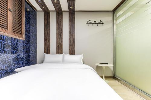 Un dormitorio con una cama blanca y una mesa. en Hotel Hue, en Incheon