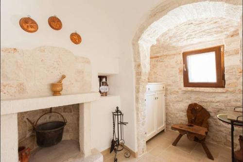 a living room with a stone fireplace and a window at Trullo Abbracciavento in Martina Franca