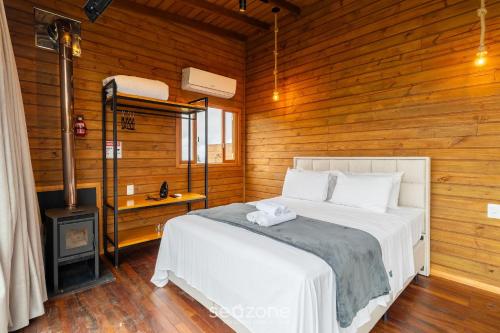 a bedroom with a white bed and a stove at Apto c/ lareira, jacuzzi e vista incrível - VST027 in São Paulo dos Pinhais