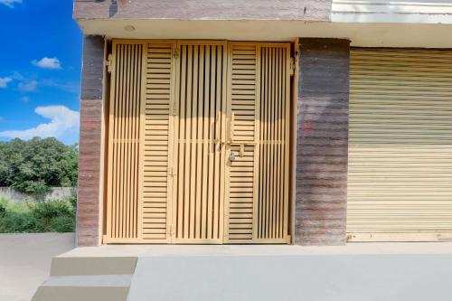 a wooden shutter door on the side of a building at SPOT ON Mahal Guest House in Paikbara