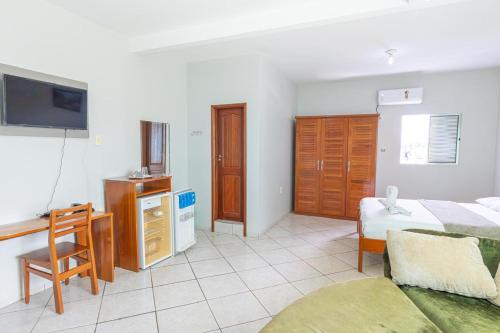 a bedroom with a bed and a desk and a tv at Swamy Hotel in Cruzeiro do Sul