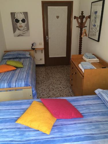 a bedroom with two beds and a dresser and a door at Bed & Breakfast Casa Marinella in Lenna