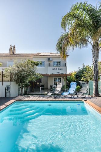 a swimming pool in front of a house with palm trees at Da Rocha House in Parchal