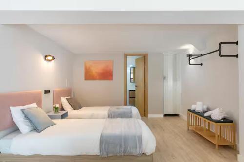 a white bedroom with two beds and a table at NUEVO Amplio dúplex en la zona del Palacio de Vista Alegre in Madrid