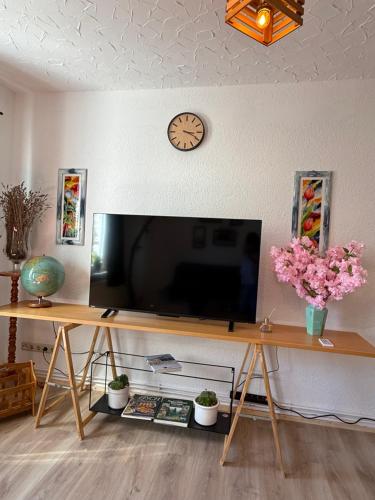 a table with a television on a wall with a clock at myna in Thale