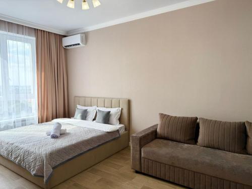 a bedroom with a bed and a couch at Светлая и уютная квартира с видом на горы, рядом с ТРЦ in Almaty