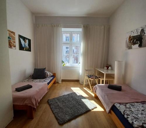 two beds in a room with a window at Paderewskiego Old Town Apartaments in Kraków