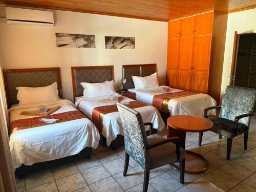 a hotel room with two beds and a table and chairs at Hotel Pension Steiner in Windhoek