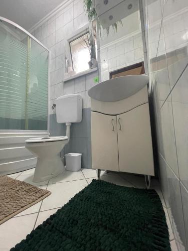 a bathroom with a toilet and a sink and a green rug at Apartman Kulenović in Kulen Vakuf