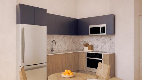 a kitchen with a white refrigerator and a table with a bowl of oranges at Flow Brickell Hotel in Miami