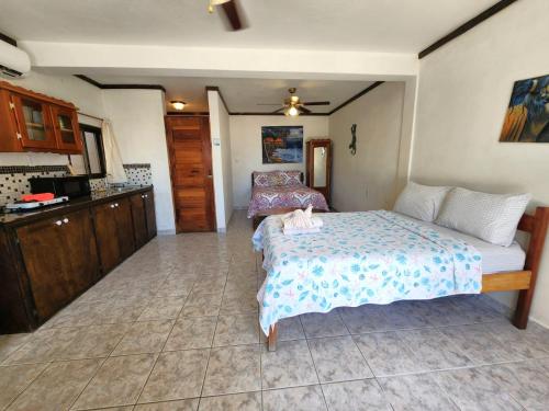 a bedroom with a large bed and a kitchen at Beach Side Condos Caye Caulker by CCVH in Caye Caulker