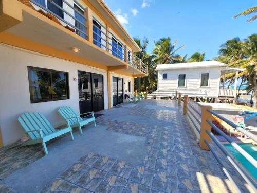 a house with two blue chairs on a patio at Beach Side Condos Caye Caulker by CCVH in Caye Caulker