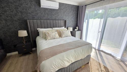 Un dormitorio con una cama grande y una ventana grande. en Thornleigh Homestead, en Pietermaritzburg