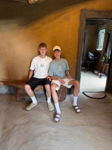 two young men sitting on a bench in a room at The Cave in Yatiyantota