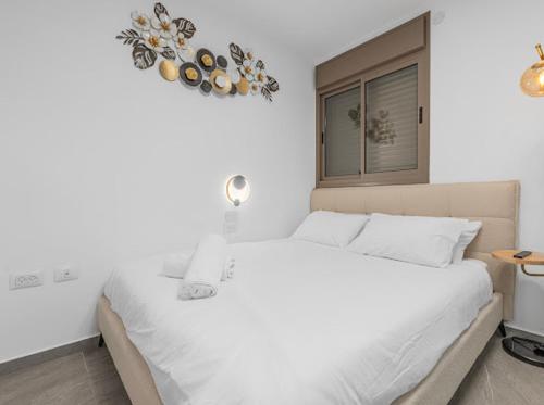 a bedroom with a white bed and a window at וילת יוקרה עם בריכה פרטית וגקוזי עם נוף לים ליד החוף של מוש in Eilat