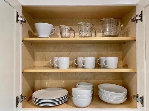a cupboard filled with plates and mugs and cups at Downtown-King Bed-Top Floor-Parking-Wi-Fi in Walnut Creek