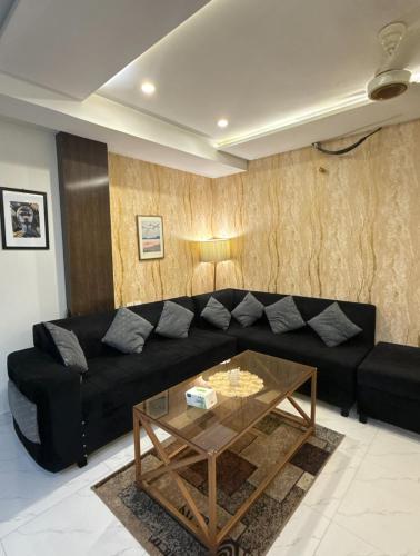 a living room with a black couch and a glass table at Luxury Eiffel View Gaming & Comfort in Lahore