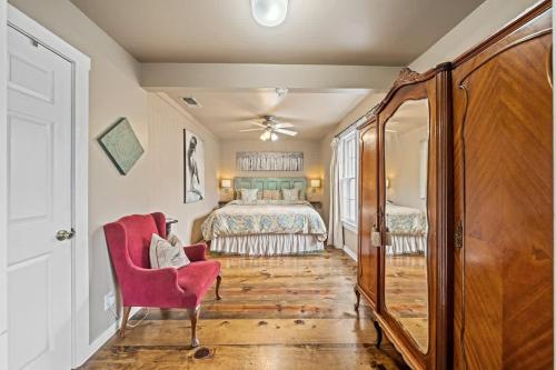 a bedroom with a bed and a red chair at Ava and Weston Combo House in Fredericksburg