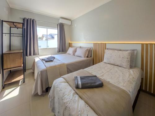 a hotel room with two beds and a window at Curta Praia da Armação - Casa Tulipa in Penha