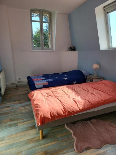 a bedroom with a bed with a red comforter and two windows at Hôtel De Ligny in Abbeville