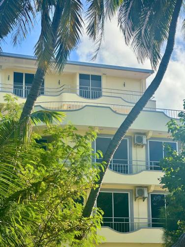 a building with palm trees in front of it at Noah Private Beach House in Himmafushi