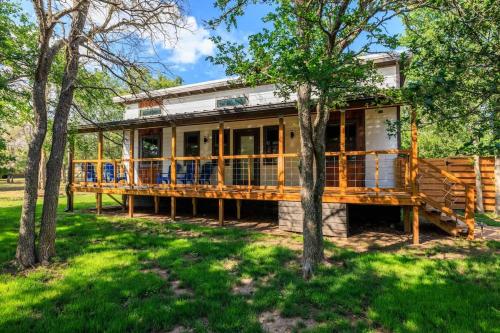 Una casa grande con una gran terraza con árboles. en Primrose Waterfront with Hot Tub, en Morris Ranch