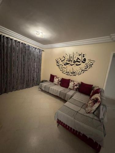 a living room with a couch and a sign on the wall at Dar Jamila in Awlād ‘Umar