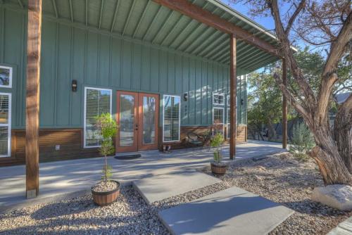 a green house with potted plants in front of it at Serene Guadalupe River Getaway-River Access! in Cranes Mill