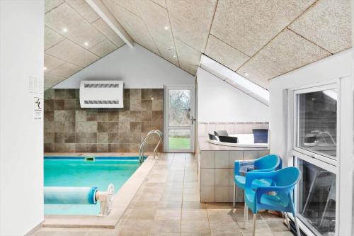a bathroom with a swimming pool and blue chairs at M235-Vaeggerlose-Kaninstien-33 in Marielyst