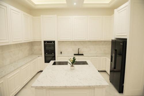 Una cocina con gabinetes blancos y un refrigerador negro. en Villa White, en Belgrado