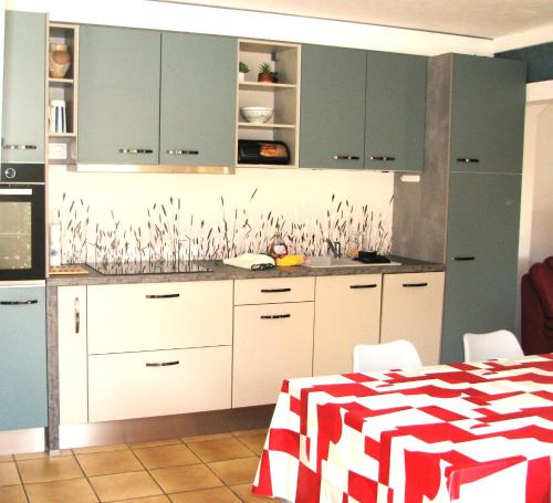 a kitchen with white cabinets and a red and white table at Maison du Combayre à Estaing in Estaing