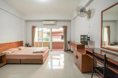 Un dormitorio con una cama, un escritorio y un espejo. en โรงแรมบ้านสวน ฟ้าใส, en Chanthaburi