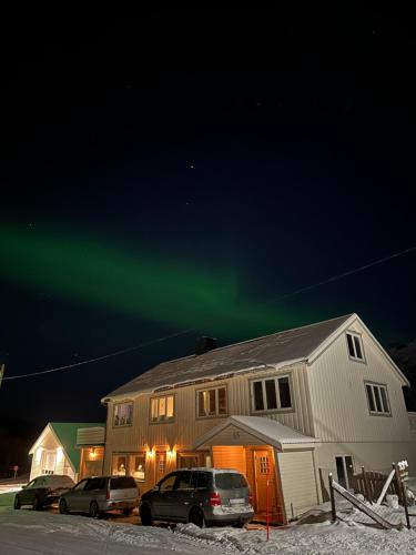 a house with cars parked in front of a house with the aurora at Northern Dream Lofoten in Hovdan