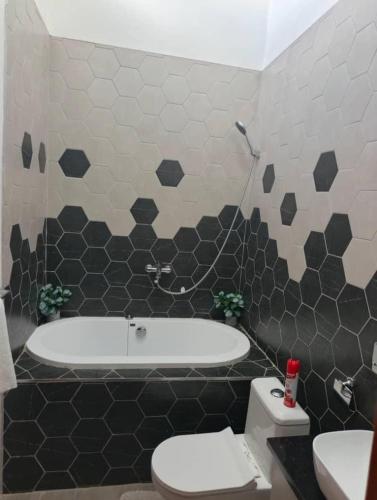 a bathroom with a tub and a toilet and a sink at Cozy and Serene in Lusaka