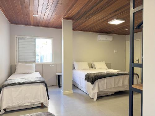 a bedroom with two beds and a wooden ceiling at Rio Jordao Hotel in Siderópolis