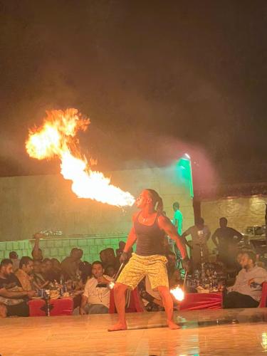 a woman is holding fire in front of a crowd at Open Sky Overnight Campsite in Desert Safari Buffet BBQ Entertainments Drinks Bone Fire 4x4 Dune Bashing in Dubai