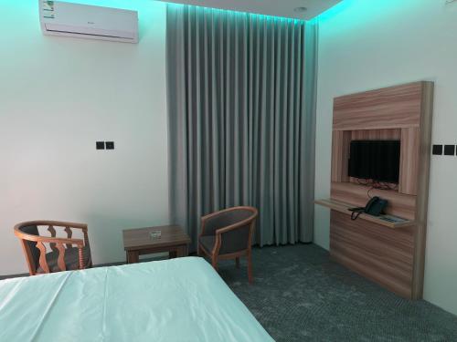 a hotel room with a bed and a tv and chairs at شقق دفادف للشقق المخدومة in Hail