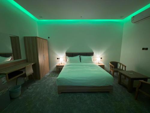 a bedroom with a bed with a green light at شقق دفادف للشقق المخدومة in Hail