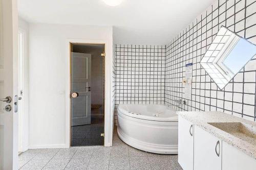 a white bathroom with a tub and a sink at M12008-Vaeggerlose-Marielyst-Strandpark-112 in Marielyst