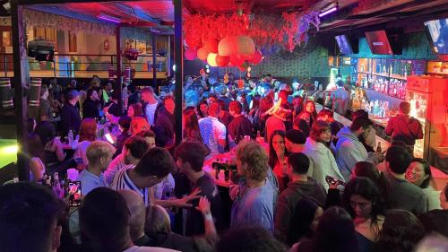 a crowd of people in a bar with red lights at Wild Rover Huacachina in Ica
