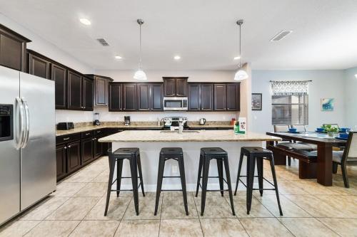 a kitchen with a large island with bar stools at 6 Bed Pool Villa in Luxury Paradise Palms Resort! in Kissimmee