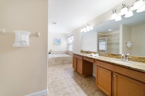 a large bathroom with two sinks and a tub at 6 Bed Pool Villa in Luxury Paradise Palms Resort! in Kissimmee