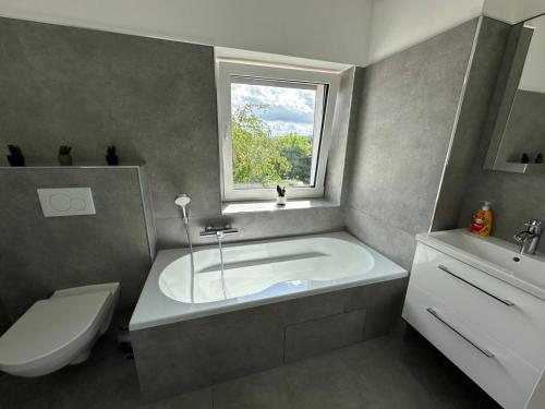 a bathroom with a tub and a toilet and a window at Große 2 Ferienwohnung Gästehaus NEUBAU Merzig 100 m2 in Merzig