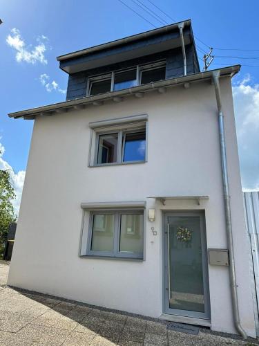 a white house with two windows and a door at Große 2 Ferienwohnung Gästehaus NEUBAU Merzig 100 m2 in Merzig